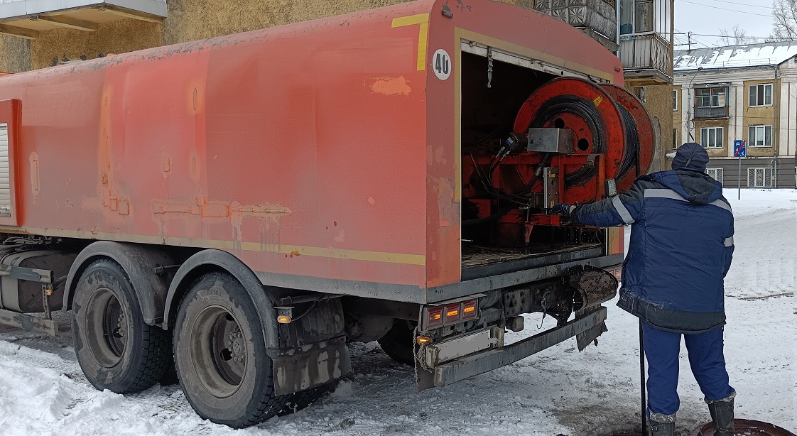 Каналопромывочная машина и работник прочищают засор в канализационной системе в Дальнегорске